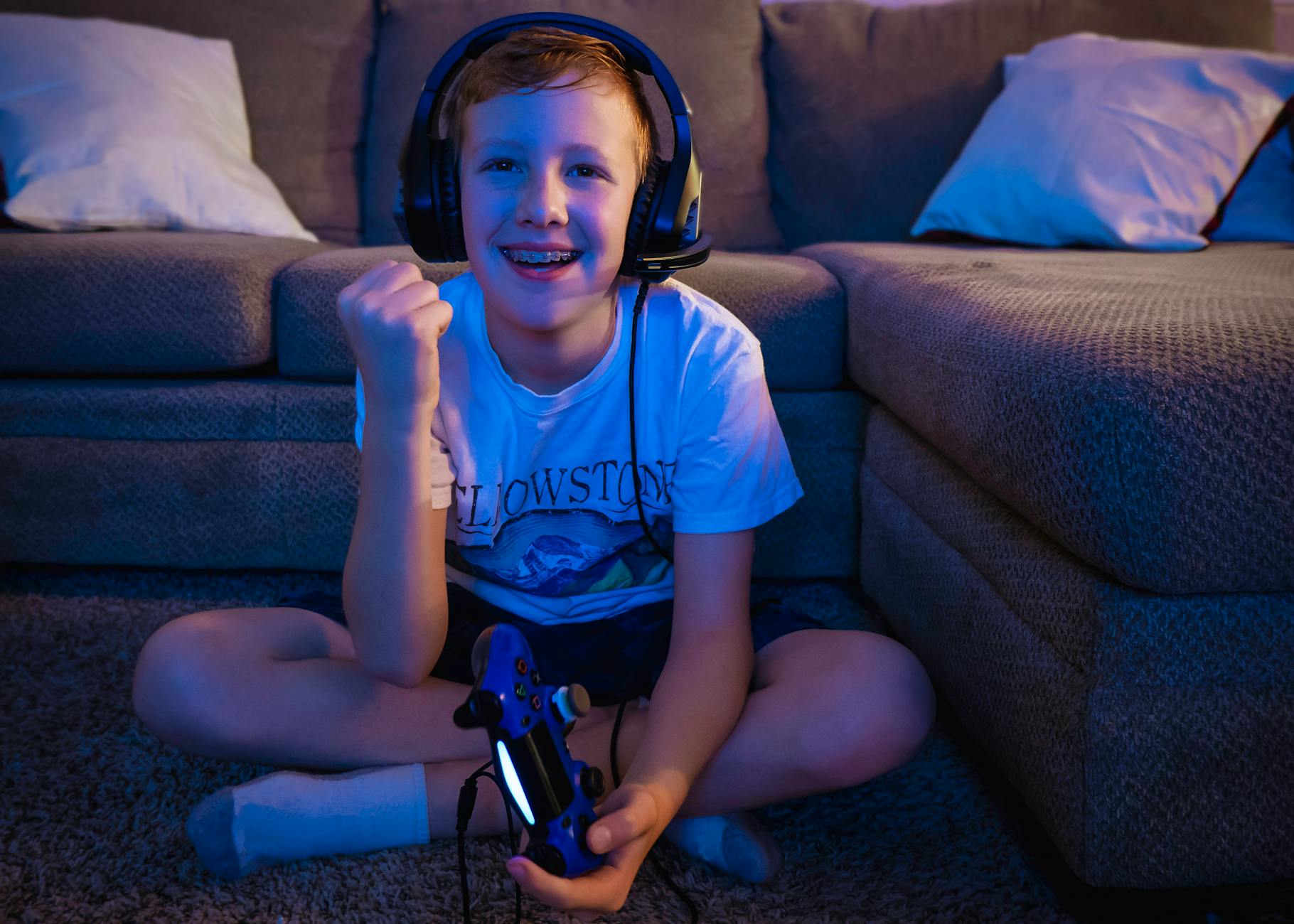 a happy boy playing video games while sitting on the floor